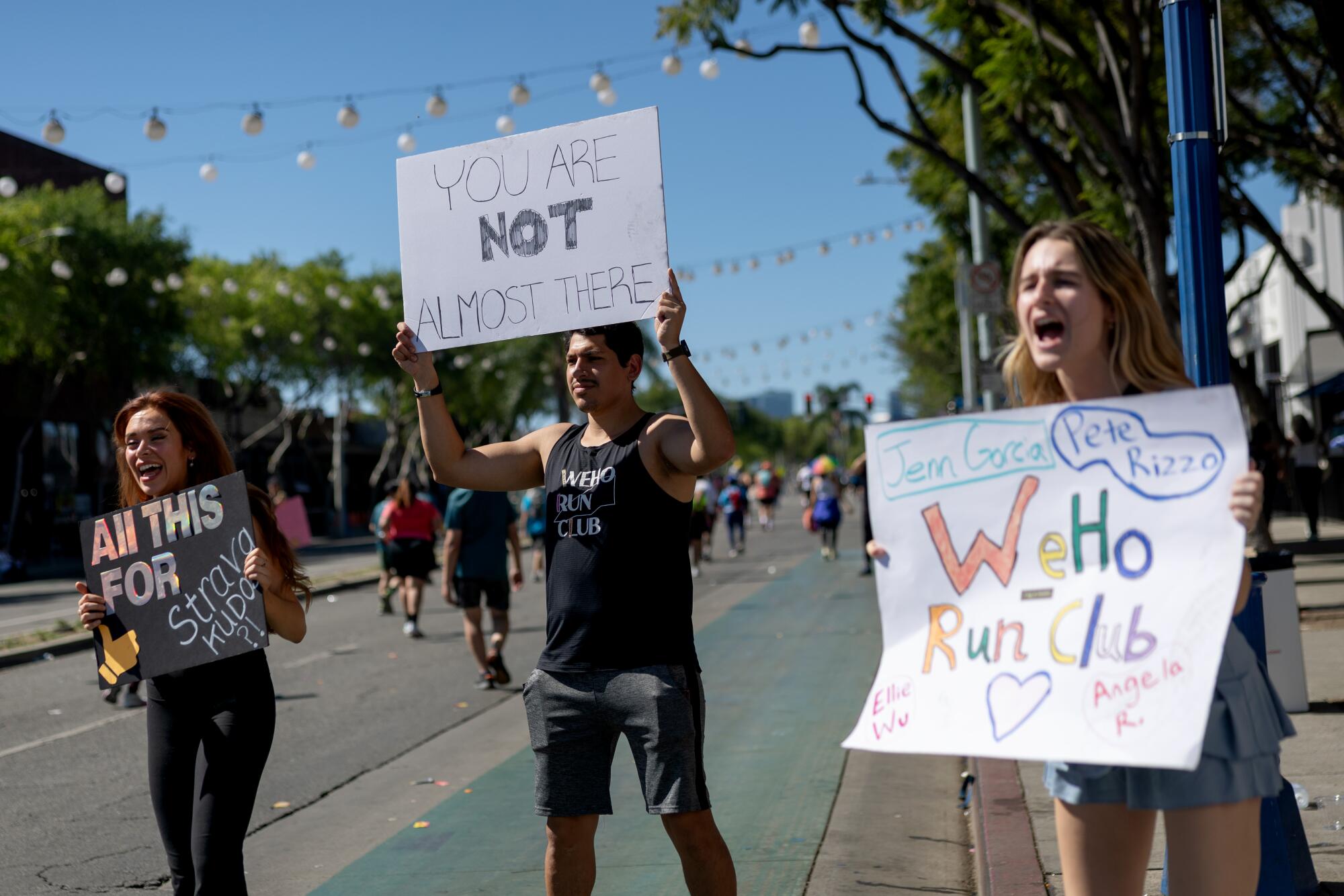Spectators stand on the race course and cheer as runners compete in the L.A. Marathon on Sunday.