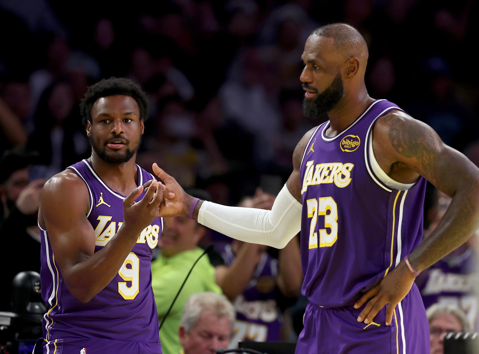 Lakers forward LeBron James greets his son, guard Bronny James, on the court during a game against the Clippers.
