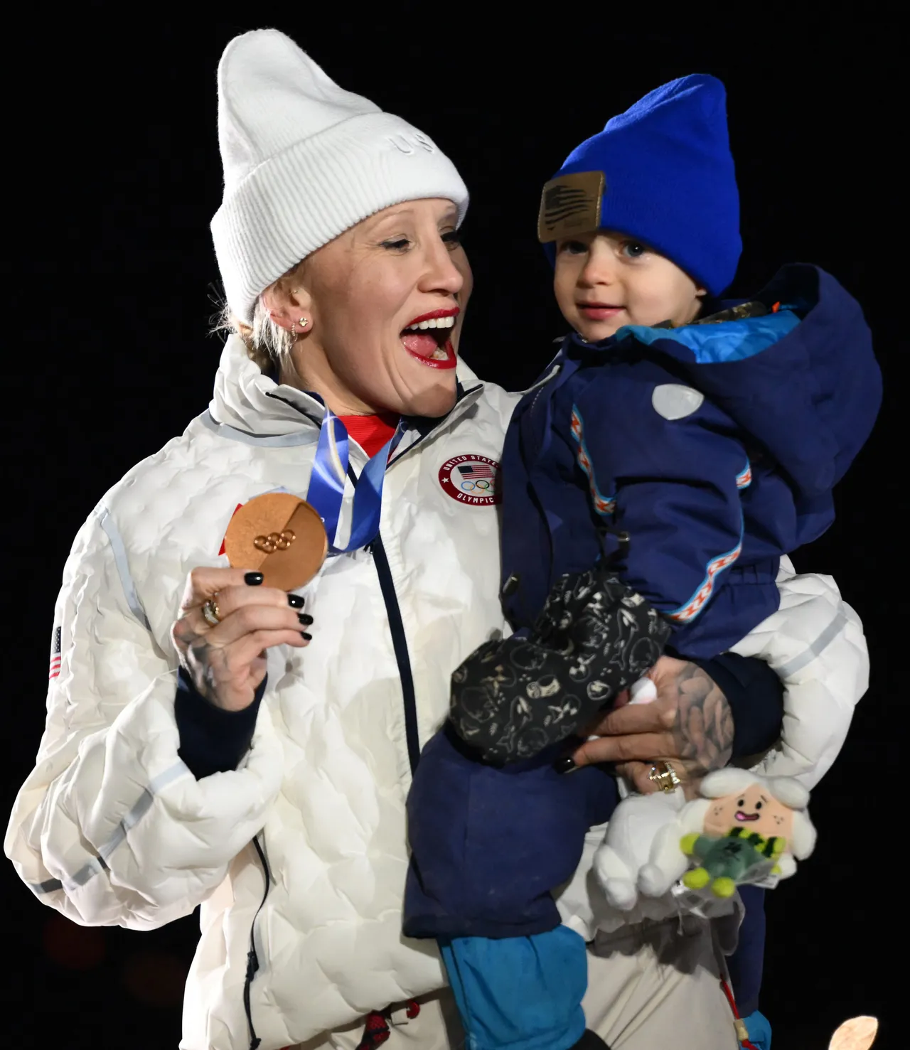 Bronze medallist USA's Kaillie Armbruster Humphries holds her son on the podium of the bobsleigh women's monobob at Cortina Sliding Centre during the Milano Cortina 2026 Winter Olympic Games in Cortina d'Ampezzo on February 16, 2026. (Photo by Marco BERTORELLO / AFP via Getty Images)