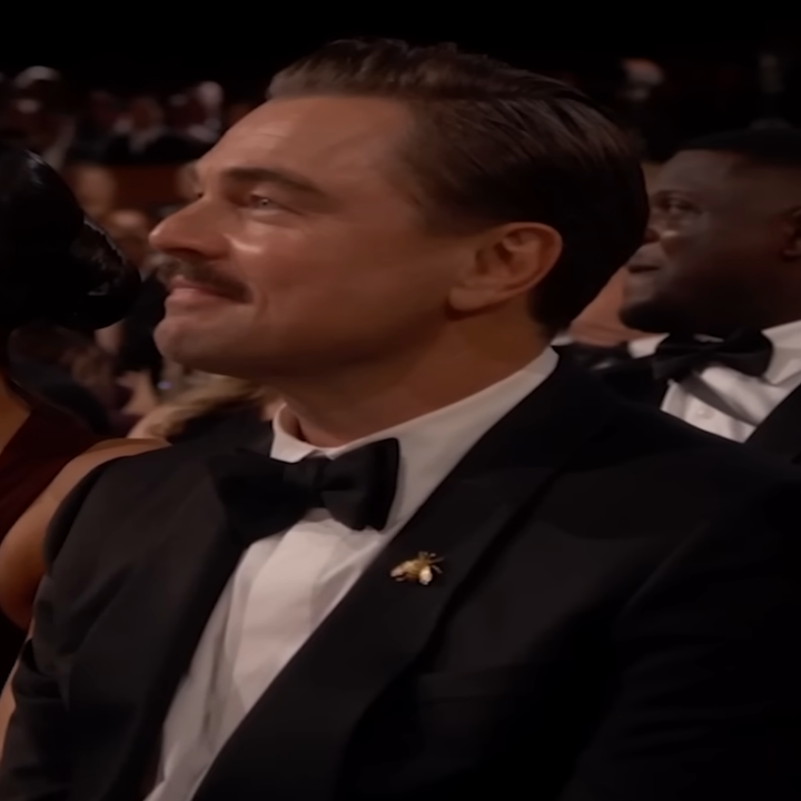 A seated man in a tuxedo with other formally dressed attendees at an award show