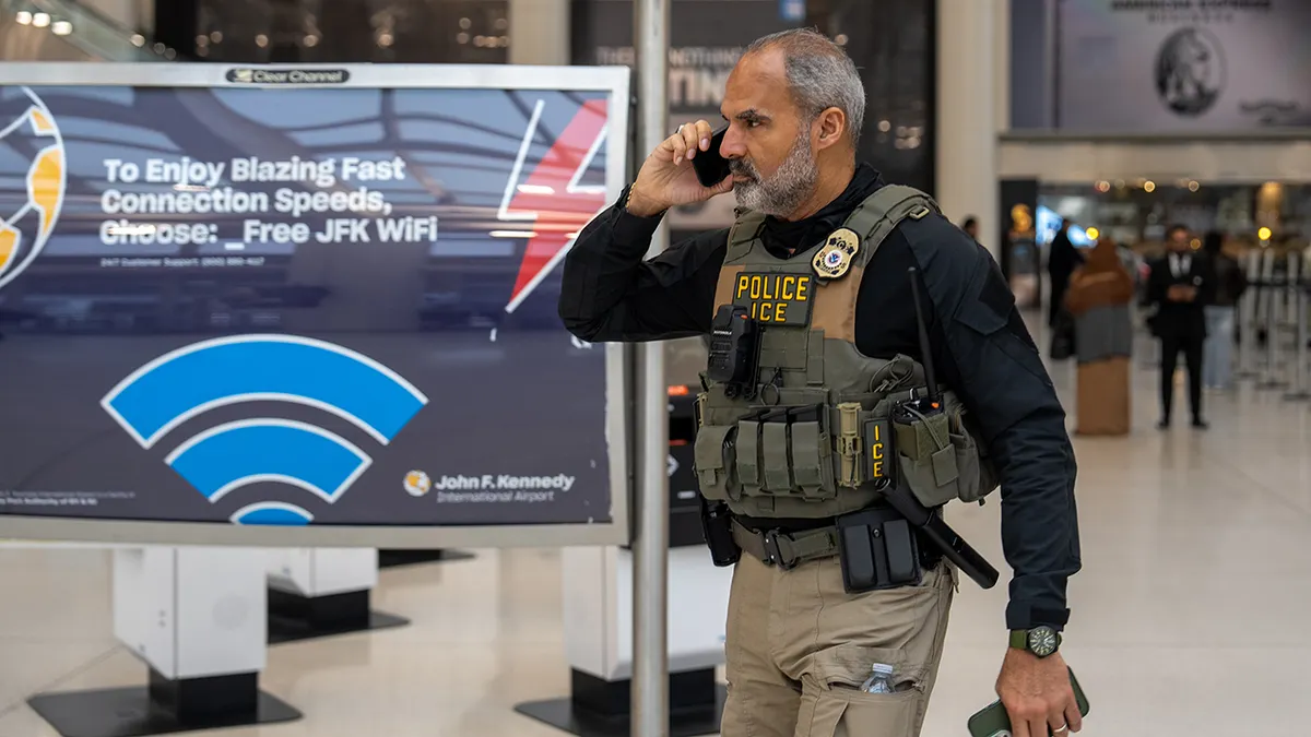 ICE agents walking through a terminal at JFK Airport.