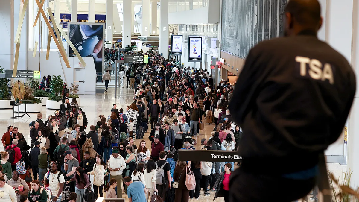 TSA agent watching passengers queue at LaGuardia airport security checkpoint
