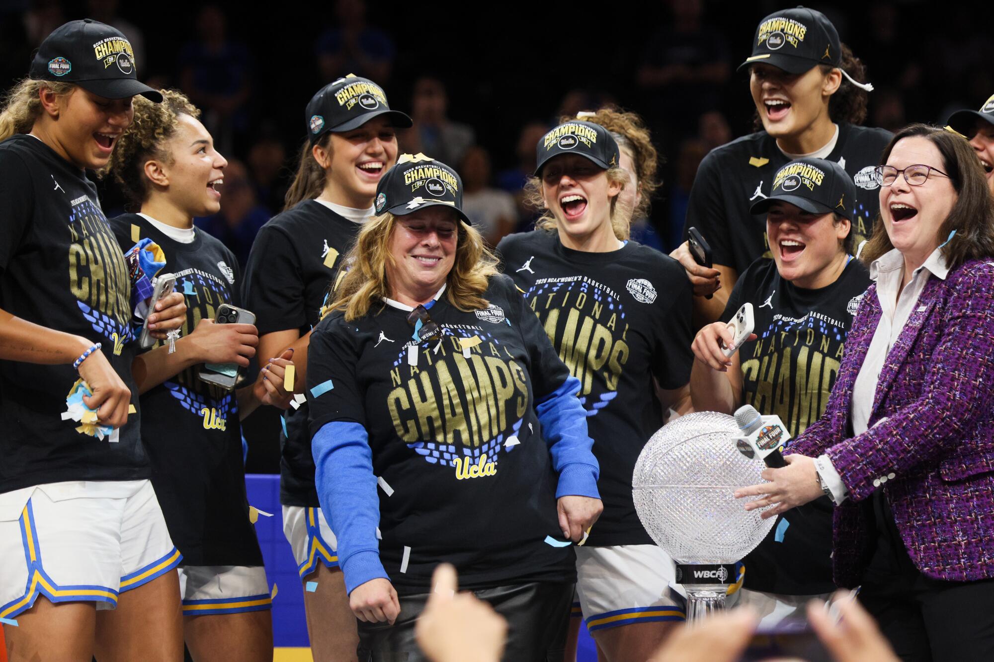UCLA coach Cori Close, center, celebrates with her players on stage.
