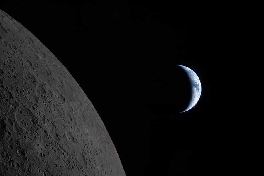 To the left, the gray, cratered surface of the moon. To the right, a crescent Earth.