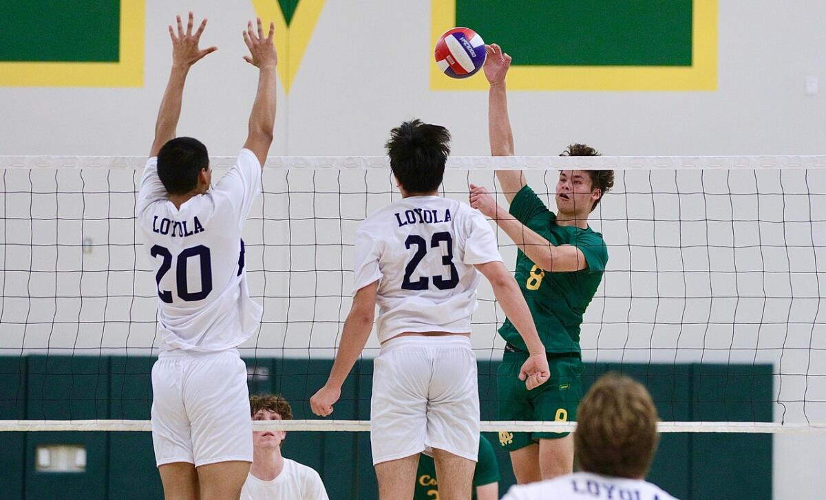 Mirca Costa High's Mateo Fuerbringer, right, tries to deliver a kill against two Loyola blockers.