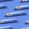 Seamless pattern of Injectors / dosing pens for subcutaneous injection of antidiabetic medication or anti-obesity medication on blue background.