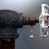 This photo shows a close-up of a water faucet with a stray drop of water dripping from it.