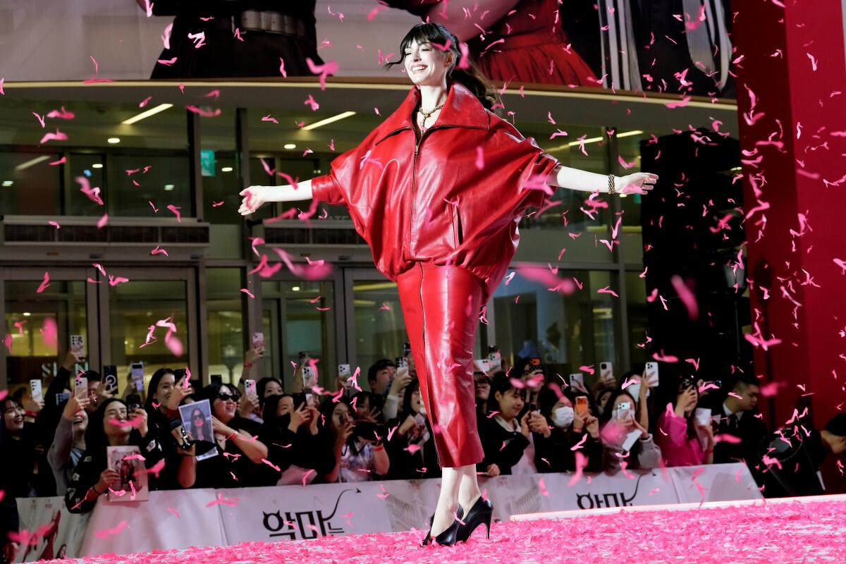 Anne Hathaway stands with arms outstretched as confetti falls. 