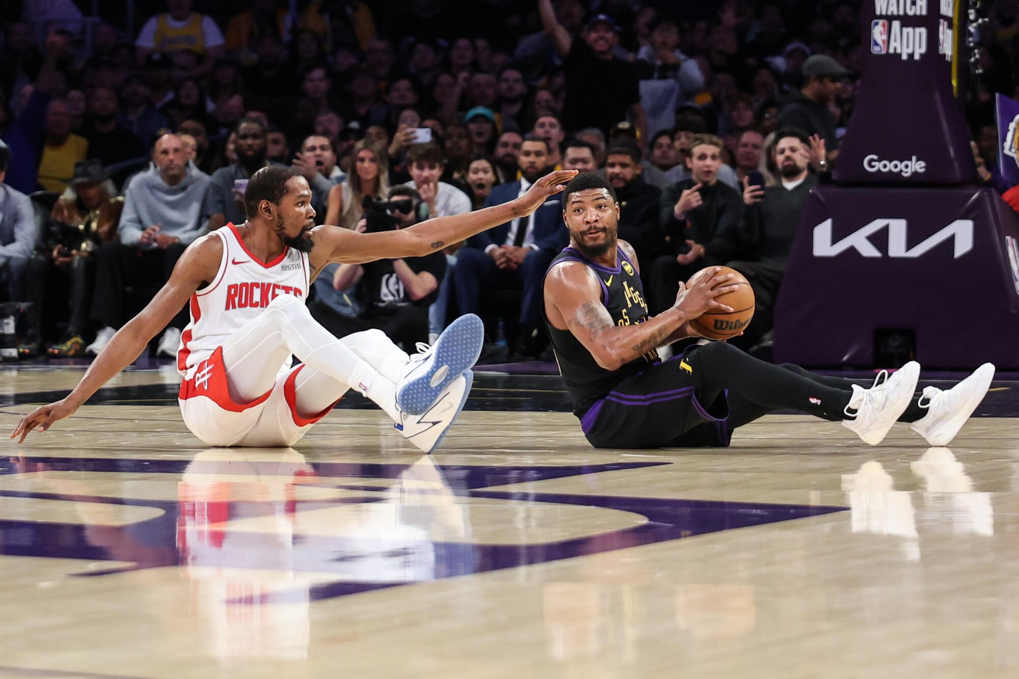 Lakers guard Marcus Smart sits on the floor with the basketball after poking it away from Houston forward Kevin Durant.