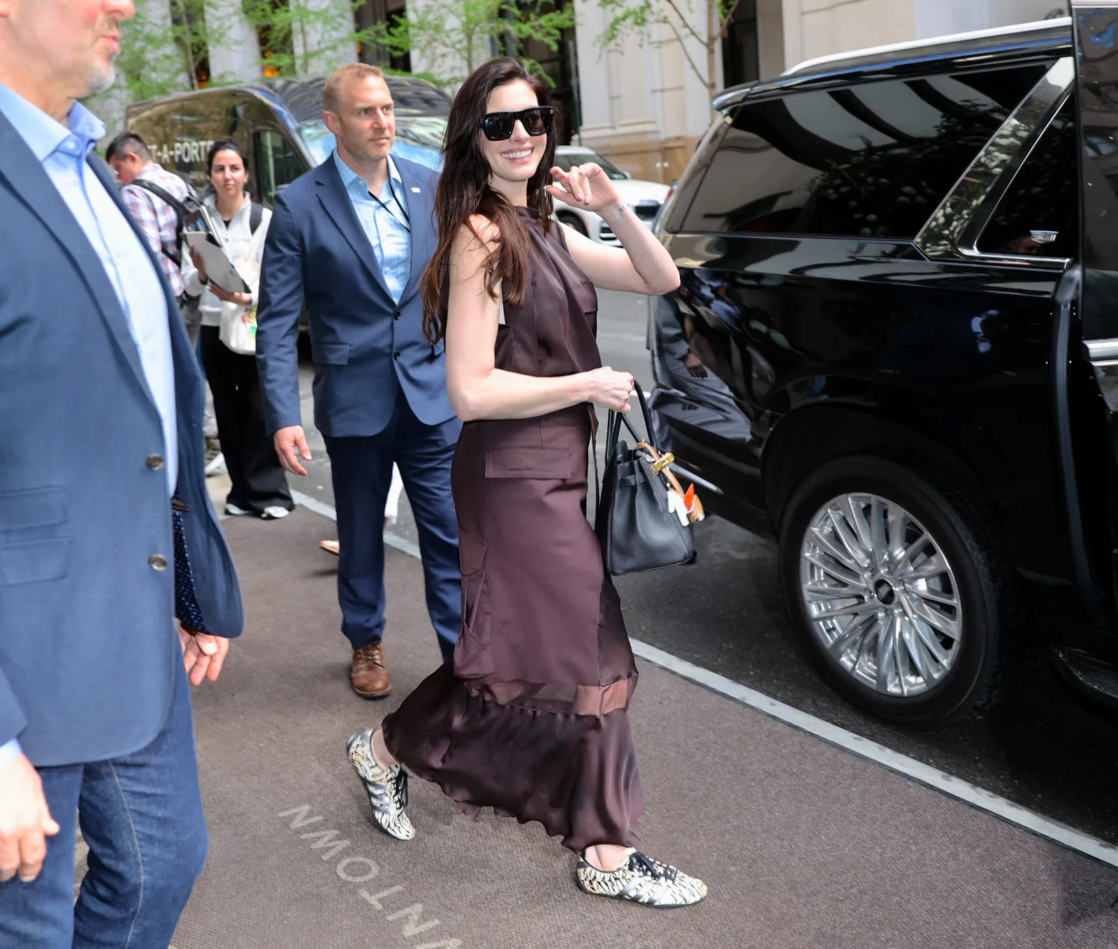 Image may contain Anne Hathaway Andrew Wilkow Clothing Footwear Shoe Formal Wear Suit Dress Adult Person and Car