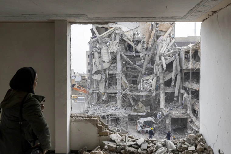 A woman looks out upon residential buildings that were destroyed a few days ago