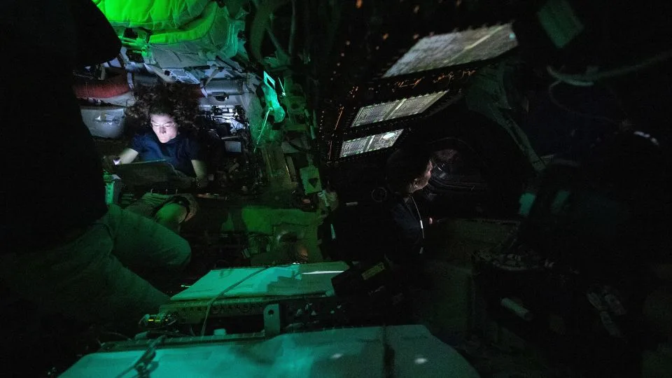 Koch reads on a tablet while Canadian Space Agency astronaut Jeremy Hansen peers out of one of Orion’s windows. - NASA