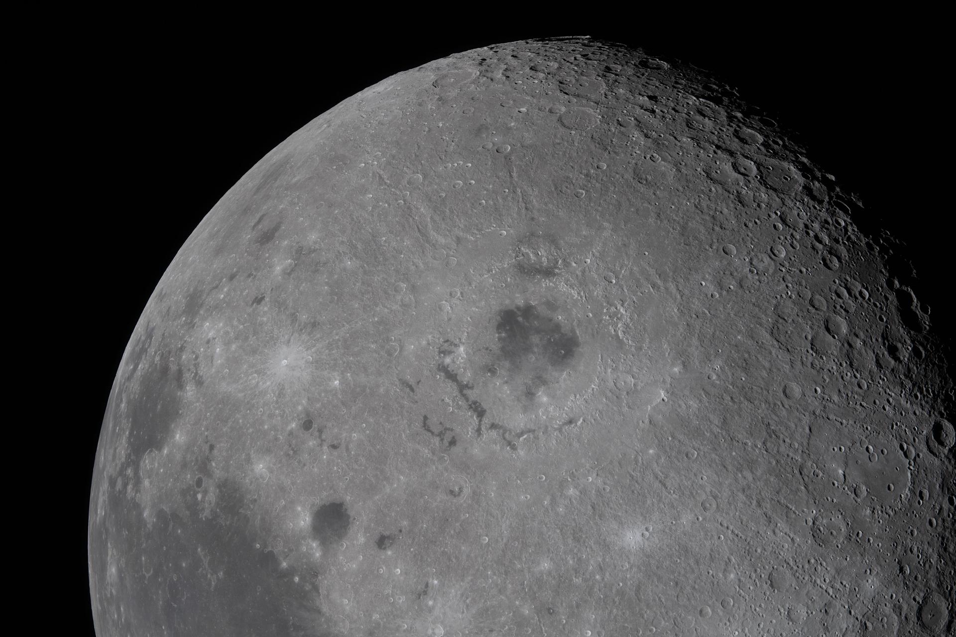 A close up of the moon in space, its dark maria and light craters obvious against the gray surface