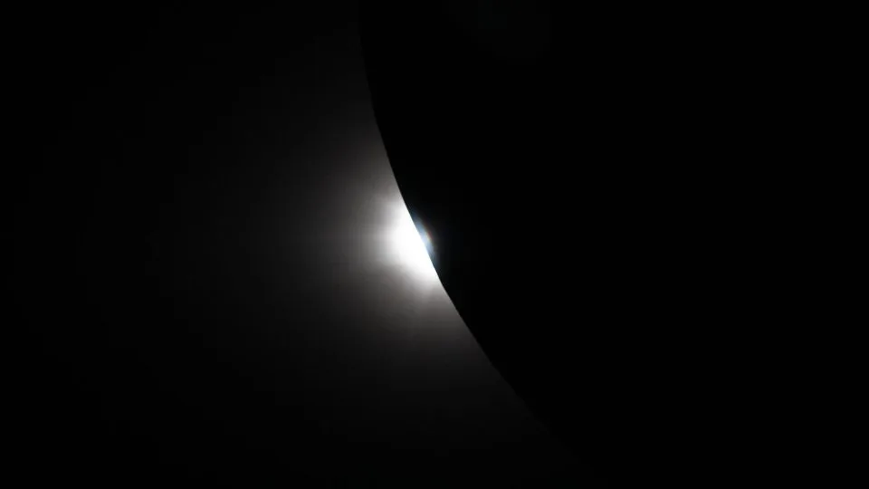 Sunlight appears from behind the moon as totality ends from the crew's perspective. - NASA