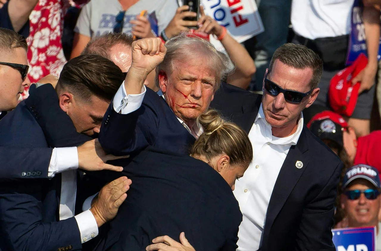 TOPSHOT - Republican candidate Donald Trump is seen with blood on his face surrounded by secret service agents as he is taken off the stage at a campaign event at Butler Farm Show Inc. in Butler, Pennsylvania, July 13, 2024. Donald Trump was hit in the ear in an apparent assassination attempt by a gunman at a campaign rally on Saturday, in a chaotic and shocking incident that will fuel fears of instability ahead of the 2024 US presidential election. The 78-year-old former president was rushed off stage with blood smeared across his face after the shooting in Butler, Pennsylvania, while the gunman and a bystander were killed and two spectators critically injured. (Photo by Rebecca DROKE / AFP via Getty Images)