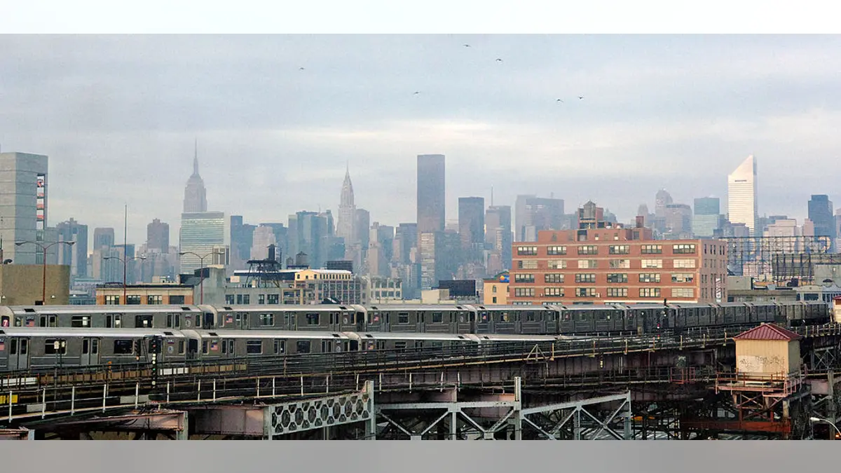 Queensboro Plaza subway station with trains arriving and departing and New York City skyline in background