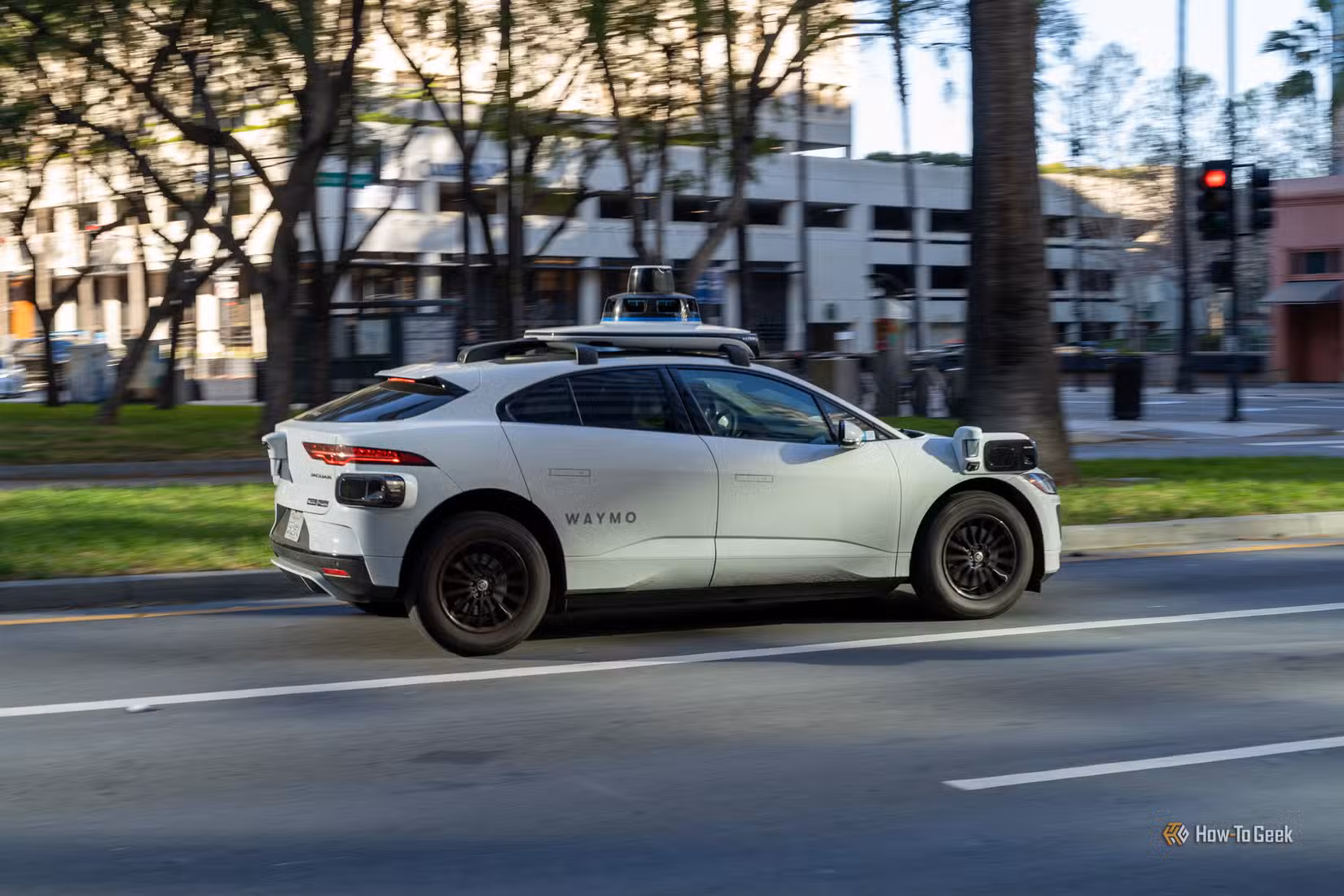 A Waymo self-driving Jaguar I-PACE SUV driving down a city street.