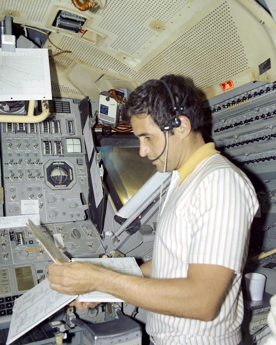 Harrison Schmitt holds documents while standing inside of a lunar module simulator (NASA)
