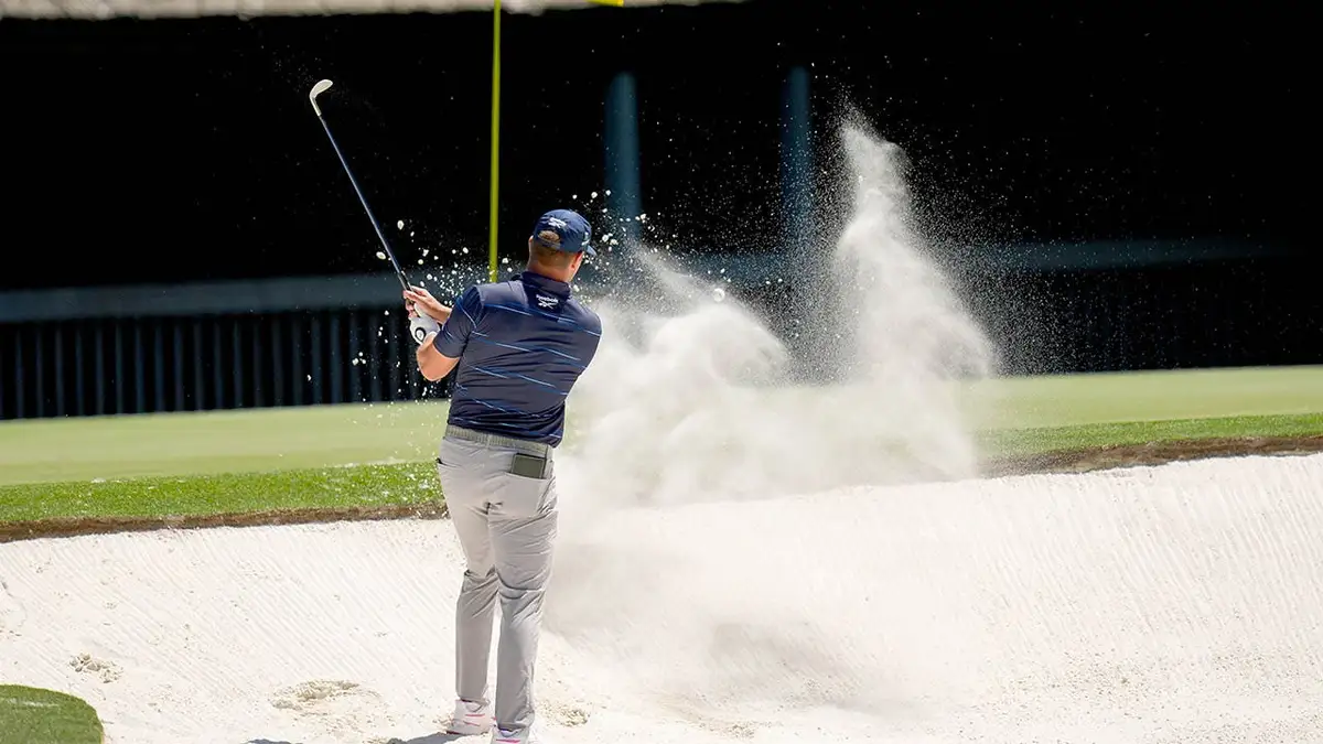 Bryson DeChambeau hitting golf ball from bunker on 11th hole at Augusta National Golf Club