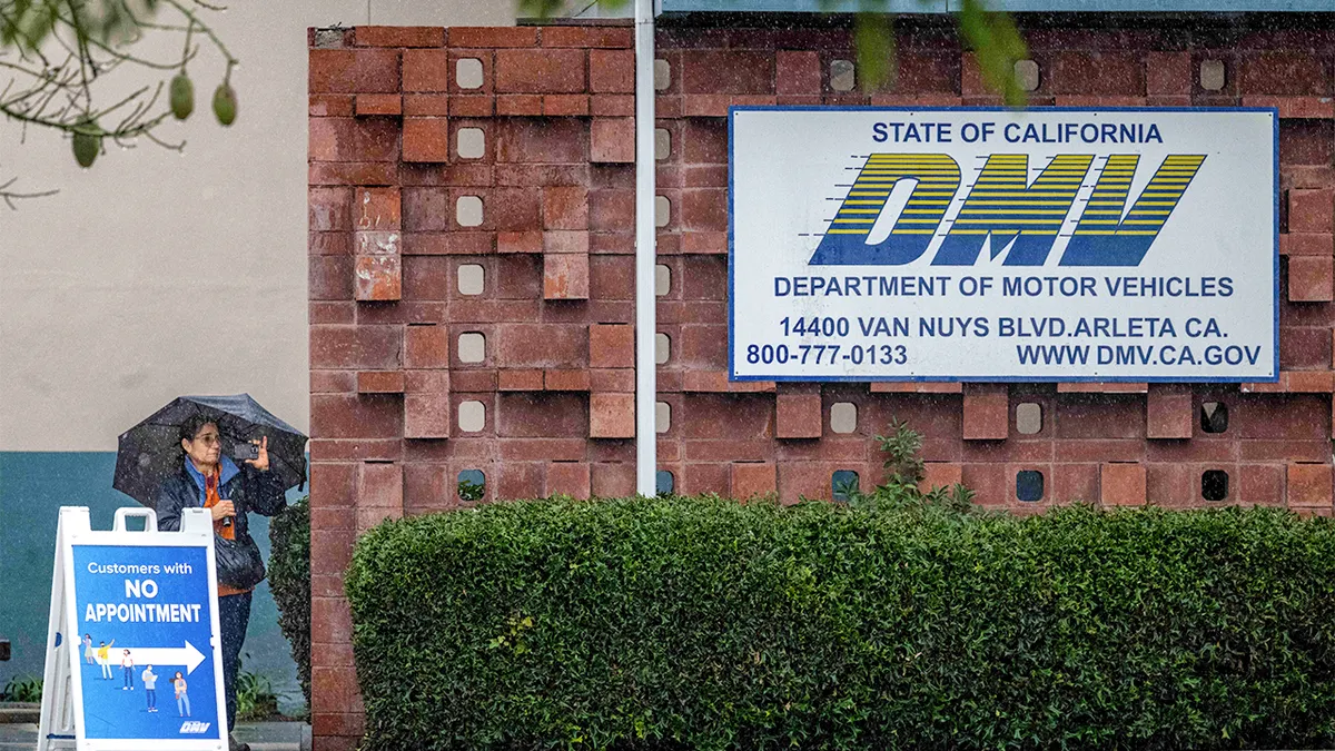 People walking through rain outside Arleta DMV office in California