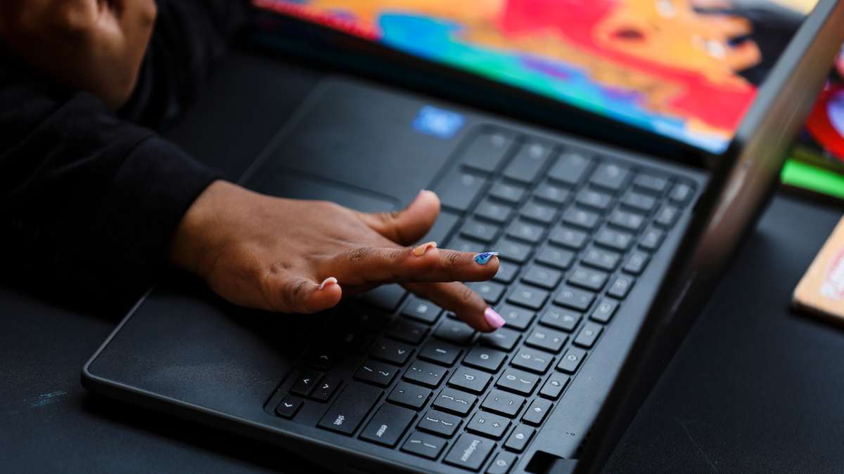 A child typing on a computer keyboard in Boston.