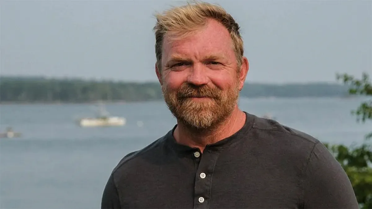 Graham Platner standing outdoors wearing a blue shirt