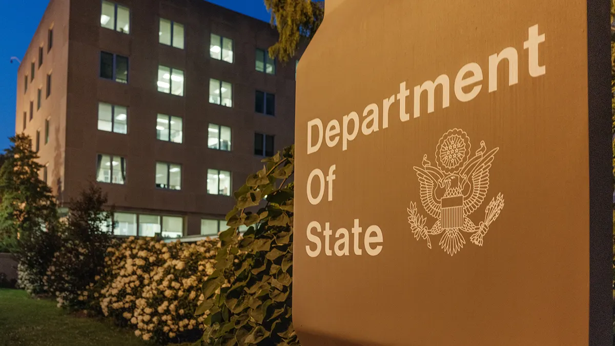 U.S. Department of State headquarters building with illuminated office lights at dusk