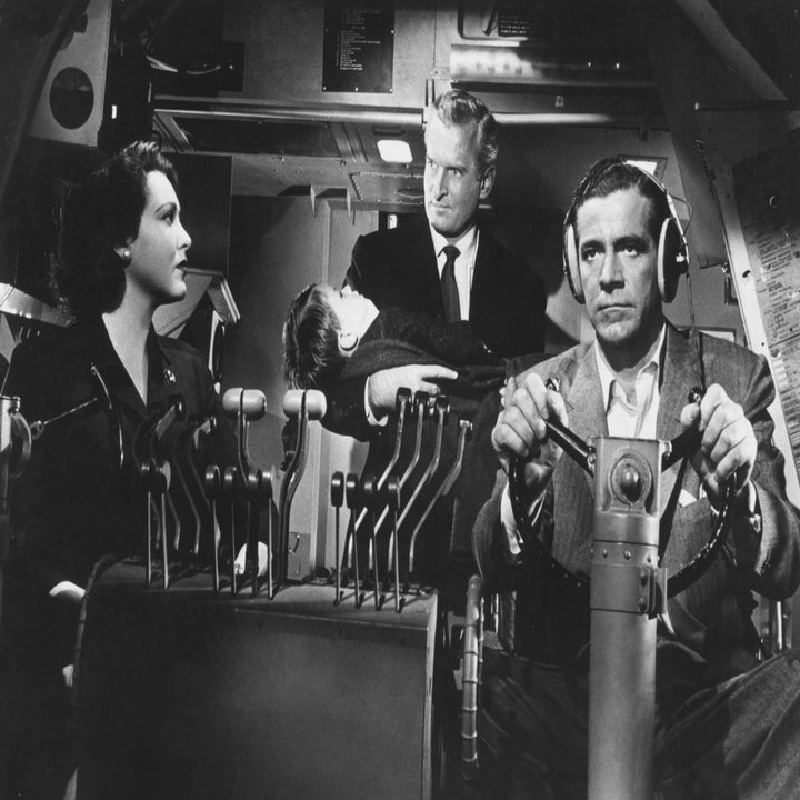 Scene from an old sci-fi movie with actors in a spaceship cockpit; one holds a child, another in pilot seat with controls, showcasing vintage film style
