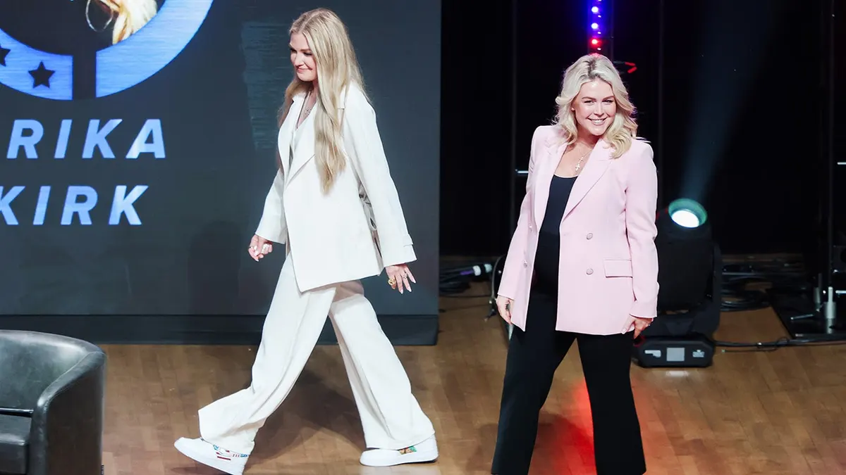 Erika Kirk and Karoline Leavitt walking onstage at George Washington University auditorium.