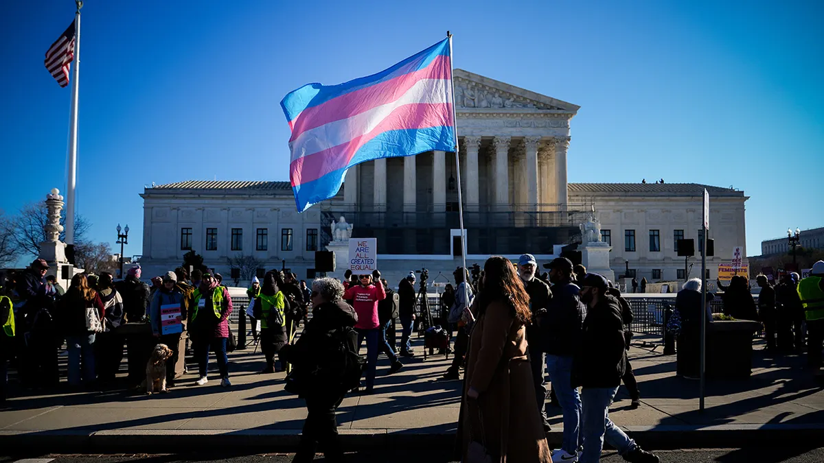 Protester carrying transgender pride flag outside Supreme Court building in Washington