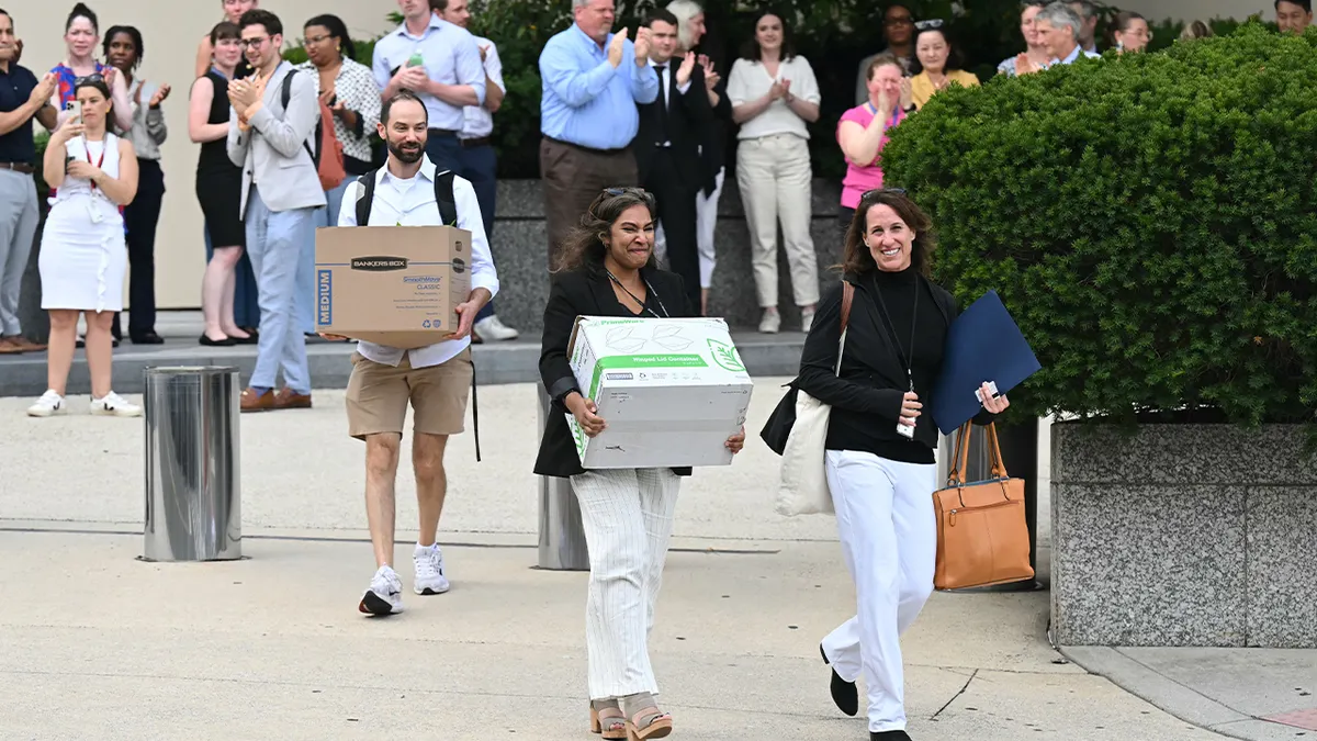 State Department workers carrying belongings leaving building in Washington, D.C.