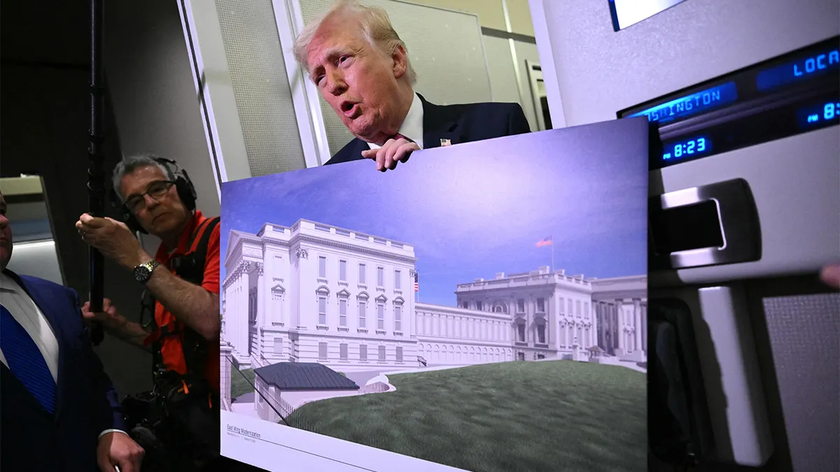 President Donald Trump holding a rendering of the East Wing modernization aboard Air Force One