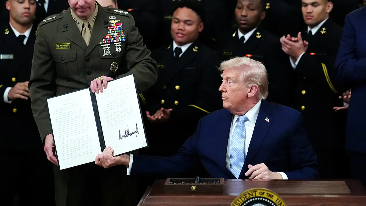President Donald Trump holding up a signed executive order in the White House East Room