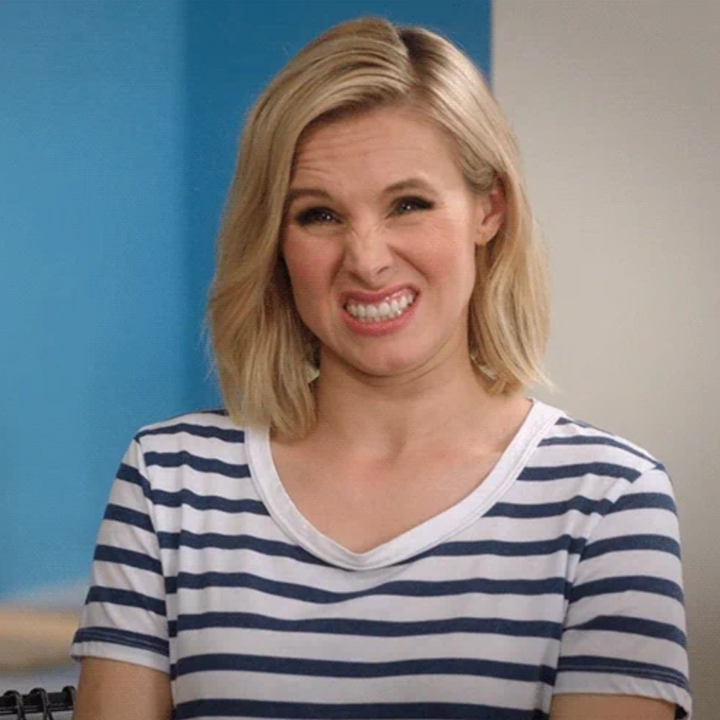 Person with a short haircut making a playful cringe expression, wearing a striped shirt in a casual setting