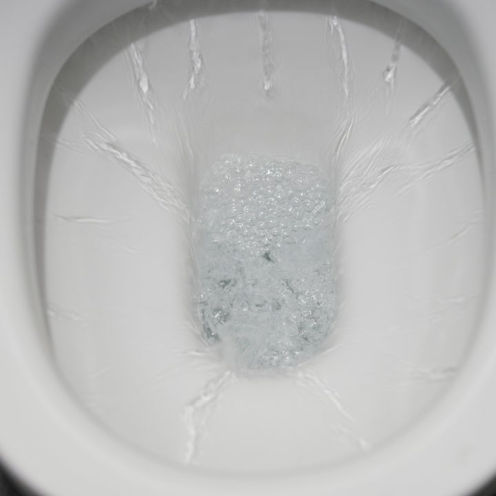 Toilet bowl with clear water and bubbles after flushing