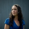 Dr. Maya Bass stands in front of a blue background.