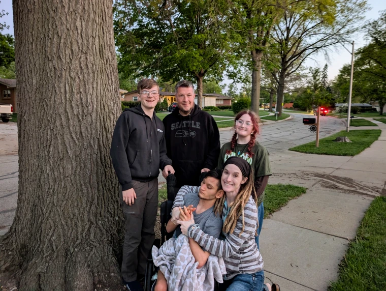 Anna Keyzer and family members pose by a tree on a sidewalk for a family portrait